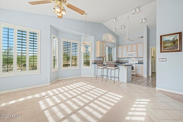 kitchen featuring a kitchen island, a kitchen bar, hanging light fixtures, ceiling fan, and white appliances