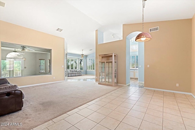 unfurnished living room with vaulted ceiling, light colored carpet, and ceiling fan