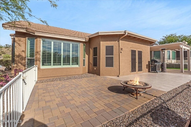 back of property featuring a pergola, a patio area, and an outdoor fire pit