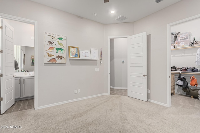 bedroom with ensuite bath, light carpet, and a closet