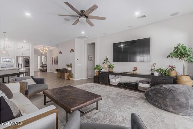 living room with ceiling fan with notable chandelier