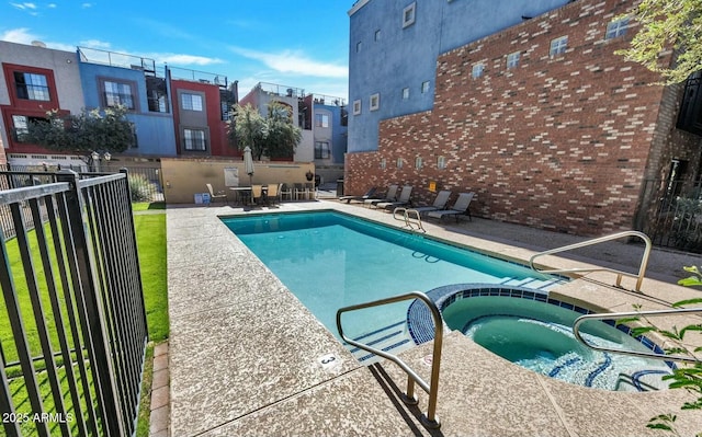 view of pool featuring a patio area, fence, and a pool with connected hot tub