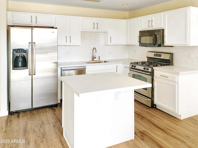 kitchen with sink, light wood-type flooring, a kitchen island, white cabinetry, and stainless steel appliances