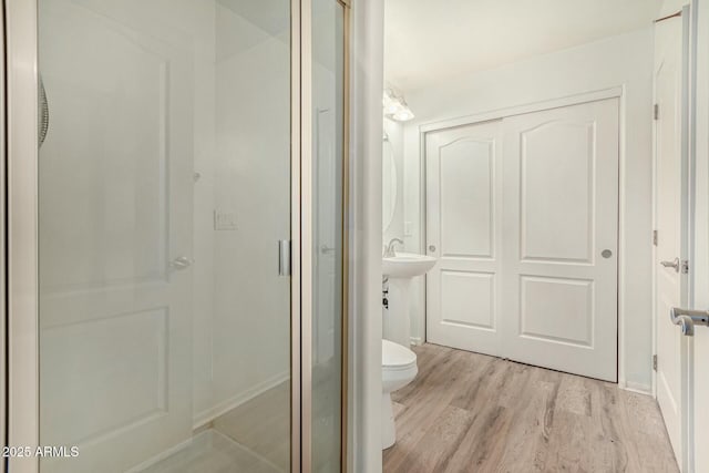 full bath featuring toilet, wood finished floors, and a shower stall