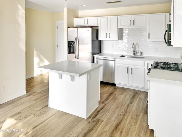 kitchen featuring a sink, decorative backsplash, light wood finished floors, and stainless steel appliances