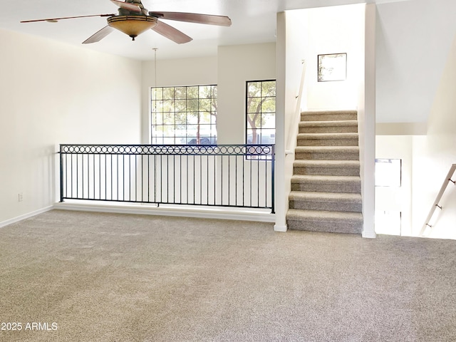 unfurnished room featuring stairway, carpet, and ceiling fan