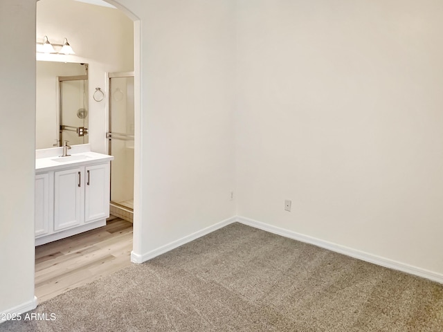 unfurnished bedroom with a sink, baseboards, arched walkways, and light carpet