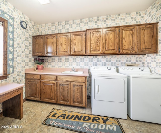 clothes washing area featuring cabinets, washer and clothes dryer, and sink