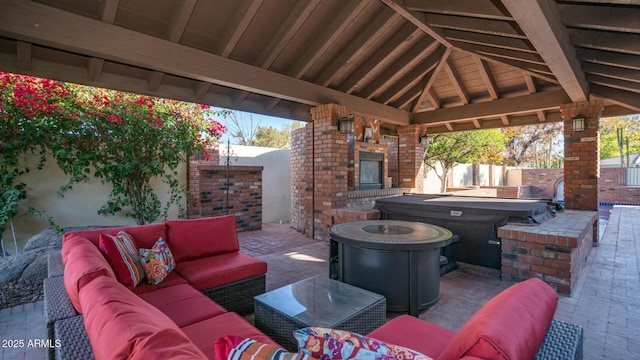 view of patio / terrace with a gazebo, a hot tub, and an outdoor living space with a fireplace