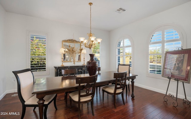 dining area featuring a chandelier, visible vents, baseboards, and wood finished floors