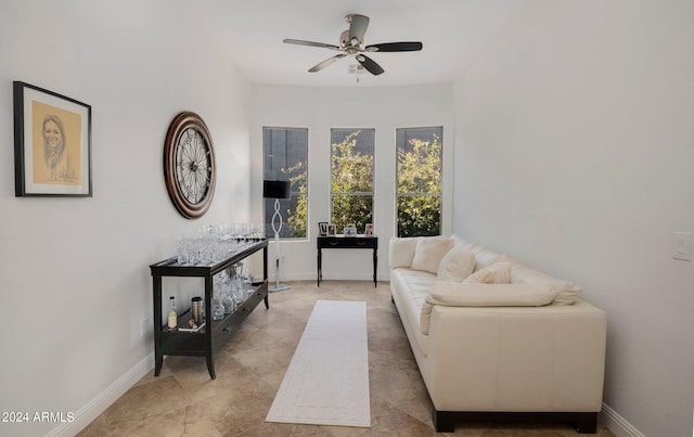 living area with baseboards and ceiling fan