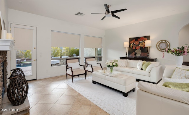 living area with light tile patterned floors, arched walkways, visible vents, and ceiling fan