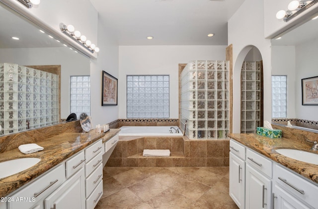 full bath featuring a sink, two vanities, a bath, and walk in shower
