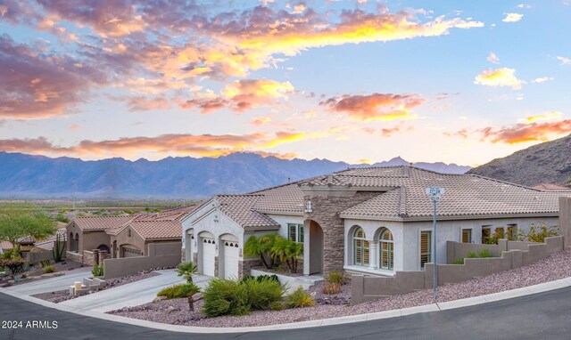 mediterranean / spanish-style home featuring an attached garage, fence, a mountain view, and stucco siding