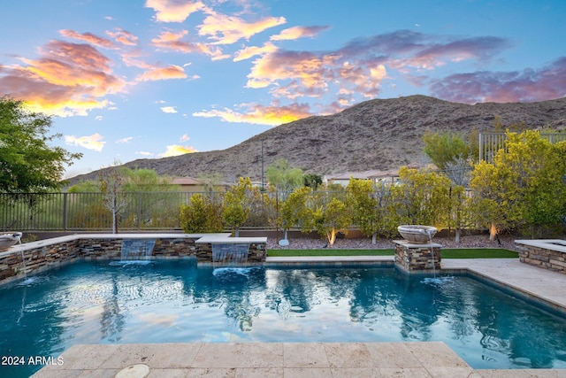 pool at dusk with a fenced in pool, a mountain view, and fence
