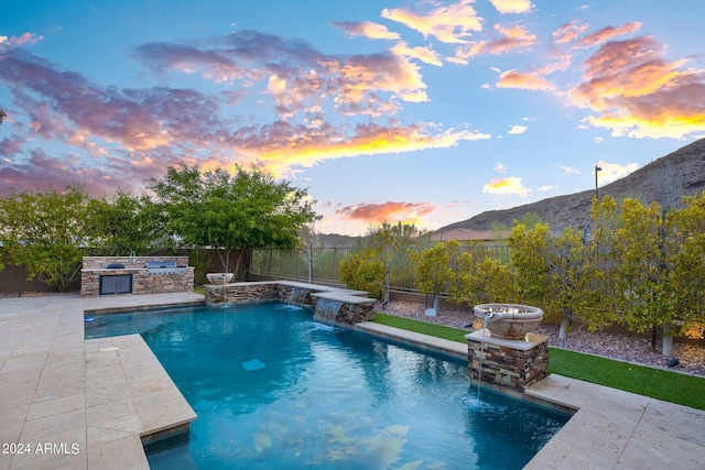 pool at dusk with a fenced in pool, area for grilling, a fenced backyard, a patio area, and a mountain view