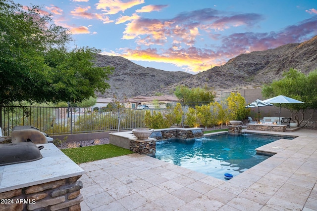 pool at dusk with a mountain view, a patio, a fenced in pool, and a fenced backyard