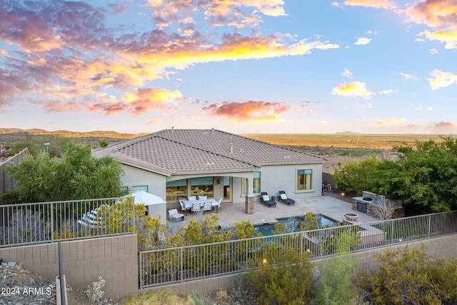 rear view of house featuring a tile roof, stucco siding, a fenced backyard, a patio area, and outdoor dining space