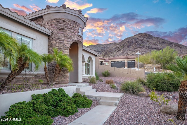 exterior entry at dusk with stucco siding, stone siding, and a mountain view