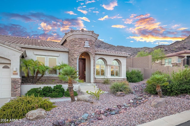 mediterranean / spanish house with stucco siding, stone siding, a mountain view, and a tile roof