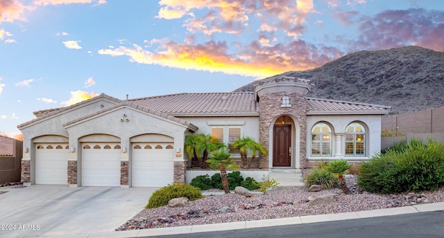 mediterranean / spanish house with a tiled roof, a garage, concrete driveway, and stucco siding