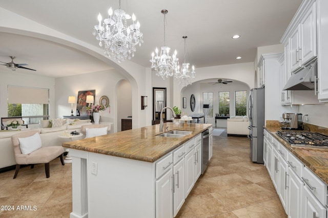 kitchen featuring under cabinet range hood, open floor plan, a sink, and ceiling fan with notable chandelier