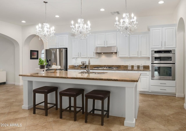 kitchen with visible vents, arched walkways, a sink, under cabinet range hood, and appliances with stainless steel finishes