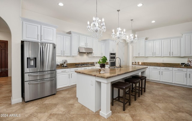 kitchen with a breakfast bar area, stainless steel appliances, under cabinet range hood, white cabinetry, and a notable chandelier
