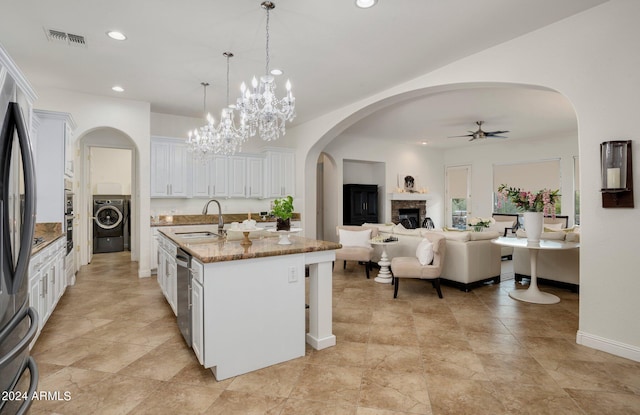 kitchen featuring visible vents, ceiling fan with notable chandelier, white cabinets, stone counters, and washer / dryer