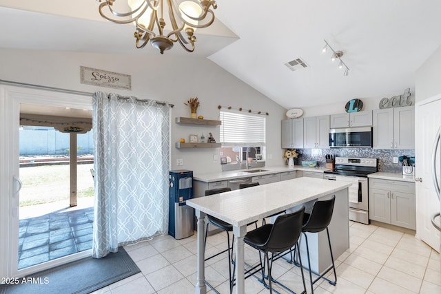 kitchen featuring visible vents, light tile patterned floors, vaulted ceiling, stainless steel appliances, and backsplash