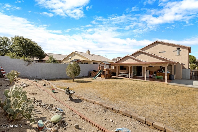back of house featuring a patio, a fenced backyard, a playground, and stucco siding