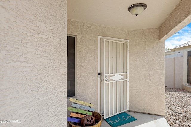 doorway to property with fence and stucco siding