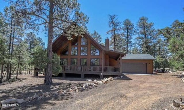 rustic home featuring an attached garage, a chimney, and dirt driveway