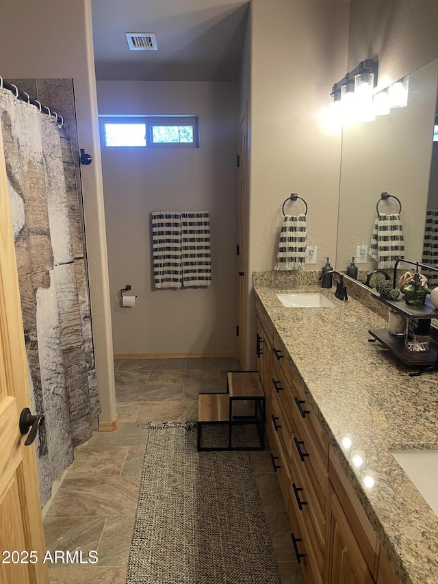 full bath with double vanity, a shower with curtain, visible vents, a sink, and stone tile flooring