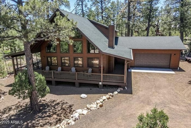 rustic home featuring roof with shingles, an attached garage, and driveway