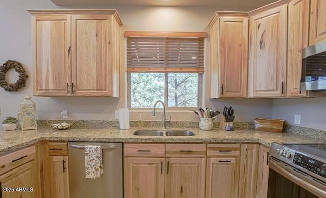 kitchen featuring a sink, appliances with stainless steel finishes, light brown cabinets, and light stone countertops