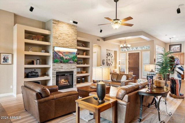 living room featuring a fireplace, built in features, ceiling fan with notable chandelier, and light wood-type flooring