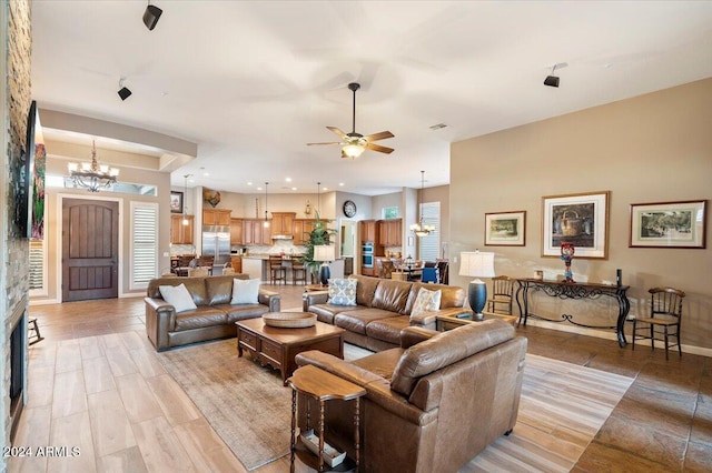 living room with light hardwood / wood-style floors and ceiling fan with notable chandelier