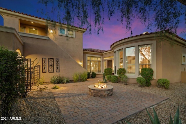 back house at dusk featuring a patio area and an outdoor fire pit