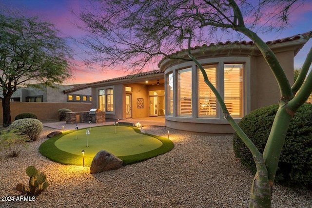 back house at dusk featuring an outdoor kitchen and a patio area