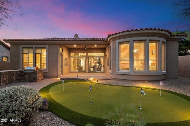 back house at dusk featuring ceiling fan and area for grilling