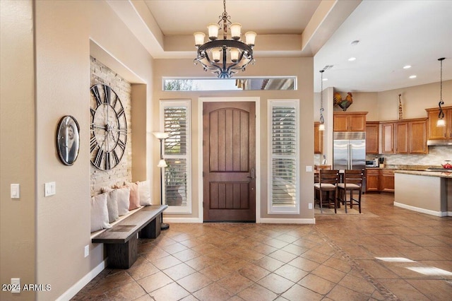 tiled foyer with a raised ceiling and a notable chandelier