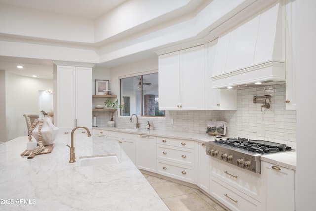 kitchen featuring light stone counters, sink, stainless steel gas cooktop, and white cabinets