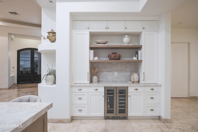 bar with white cabinets, light stone counters, wine cooler, and backsplash