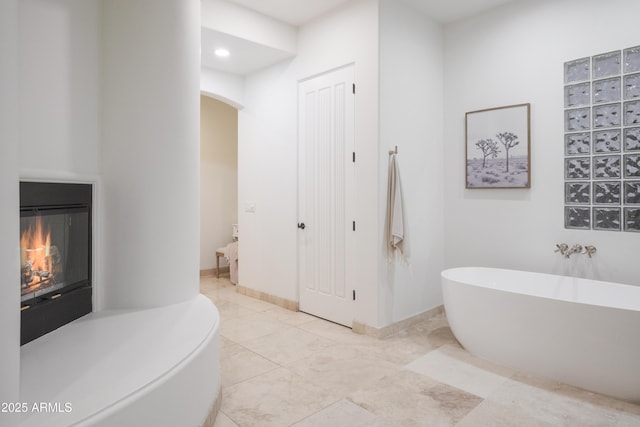 bathroom featuring a bath and a fireplace