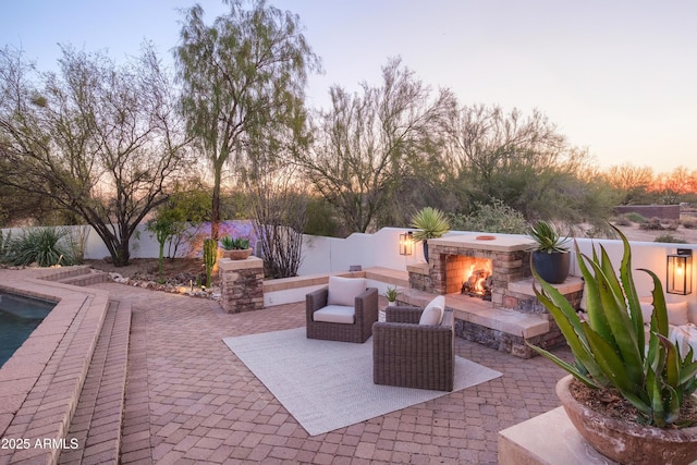 patio terrace at dusk featuring an outdoor stone fireplace