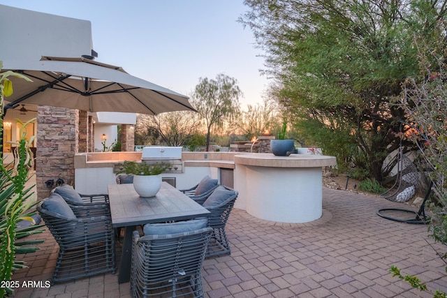 patio terrace at dusk featuring area for grilling, grilling area, and exterior bar