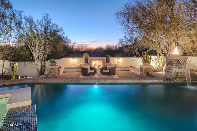 pool at dusk featuring outdoor lounge area, a patio, and pool water feature