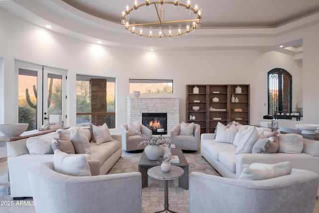 living room featuring a high ceiling, a stone fireplace, french doors, and a tray ceiling