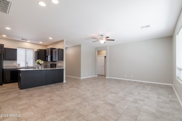 kitchen featuring ceiling fan, black stove, sink, and a kitchen island